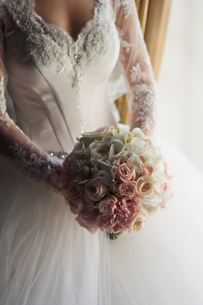 La mariée en robe luxueuse détient un bouquet d&#39;orchidées blanches et de roses roses