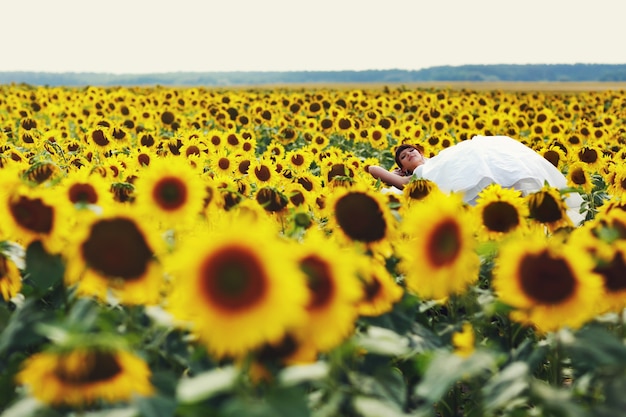 Photo gratuite la mariée se trouve sur les tournesols dans une journée ensoleillée