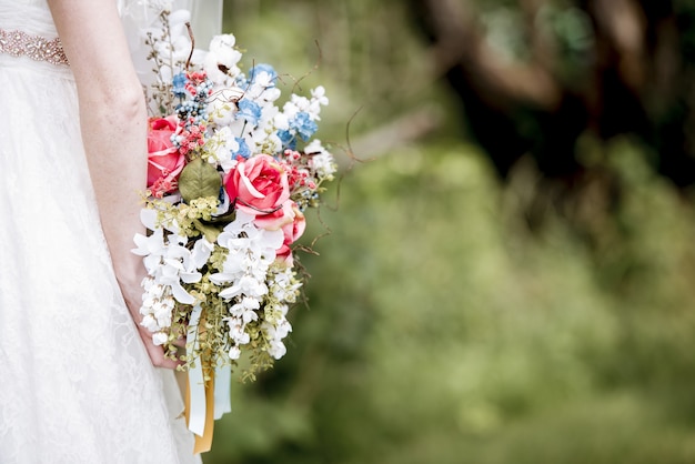 Mariée tenant le bouquet de fleurs derrière elle
