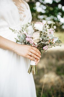 Mariée tenant le bouquet de mariage avec des fleurs blanches et roses