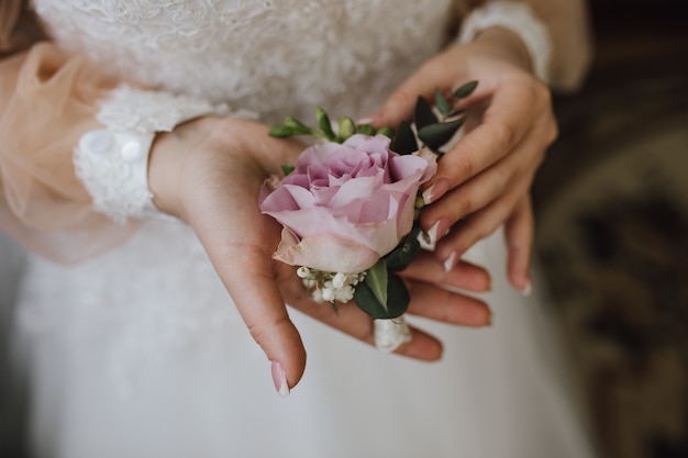 La mariée tient un butonholle avec rose rose