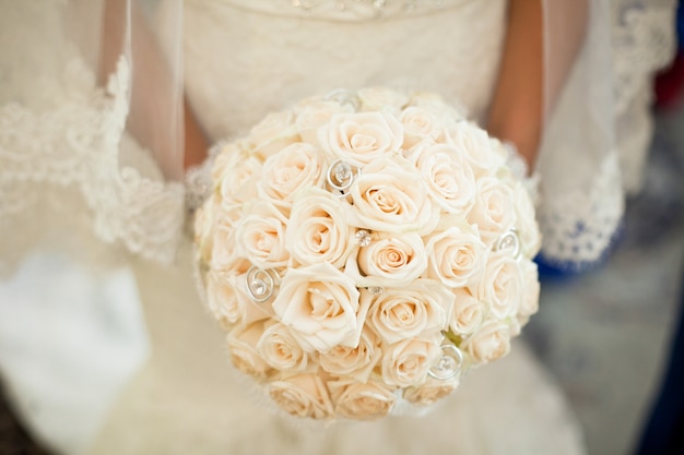 La mariée tient un magnifique bouquet de mariage fait de roses crème et