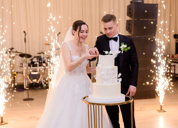 Les mariés coupant le gâteau de mariage ensemble