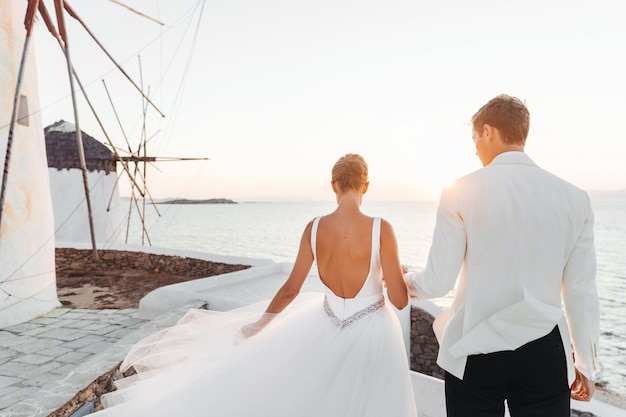 Les mariés marchent vers le coucher de soleil sur la mer