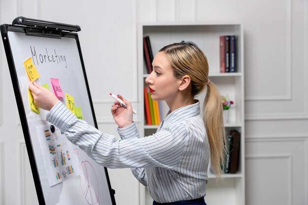 Marketing jeune femme d'affaires mignonne en chemise rayée au bureau écrivant sur un tableau blanc