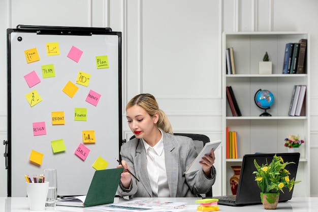 Marketing Jeune Jolie Fille Blonde En Costume Gris Au Bureau En Lisant Un Livre