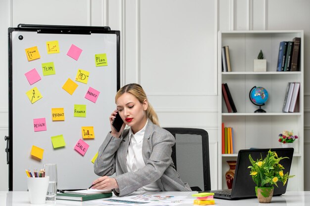 Marketing jolie jeune femme d'affaires en costume gris au bureau prenant des notes au téléphone