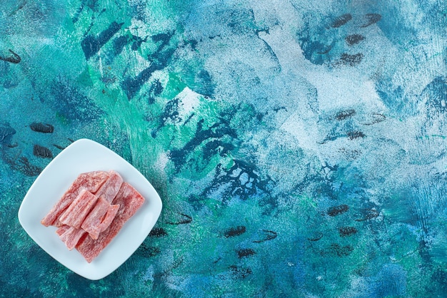 Marmelade rouge dans une assiette, sur la table bleue.