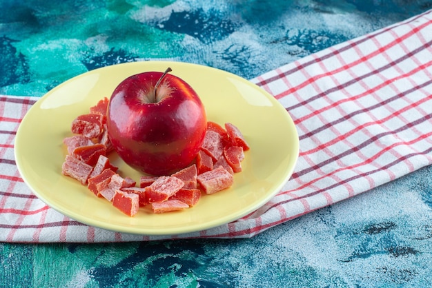 Photo gratuite marmelade rouge en tranches et pomme dans une assiette sur un torchon , sur la table bleue.