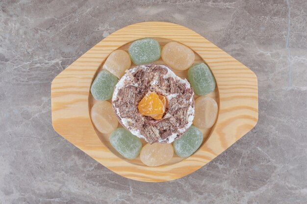 Marmelades autour d'un petit gâteau sur un plateau en bois sur marbre