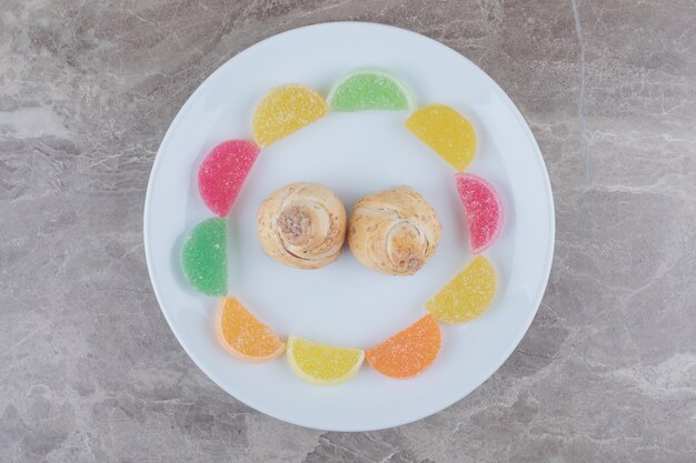 Marmelades autour de petits gâteaux sur un plateau sur marbre