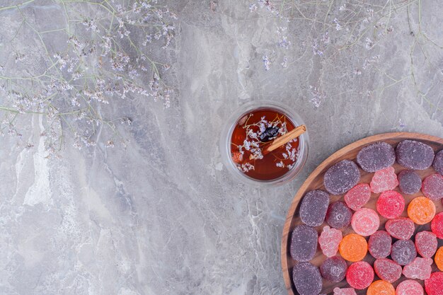Marmelades colorées dans un plateau en bois avec une tasse de thé.