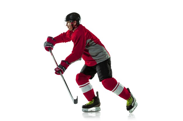 Marquer un but. Joueur de hockey masculin avec le bâton sur le court de glace et le fond blanc. Sportif portant un équipement et un casque pratiquant. Concept de sport, mode de vie sain, mouvement, mouvement, action.