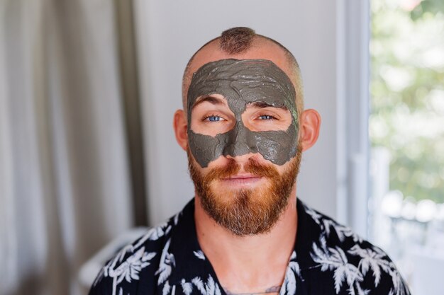 Masque d'argile sur le visage de jeune homme beau dans une clinique de beauté