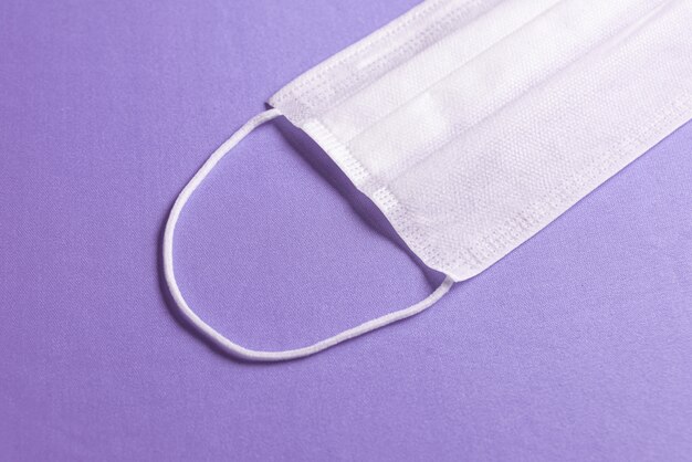 Masque chirurgical sur fond violet minimaliste