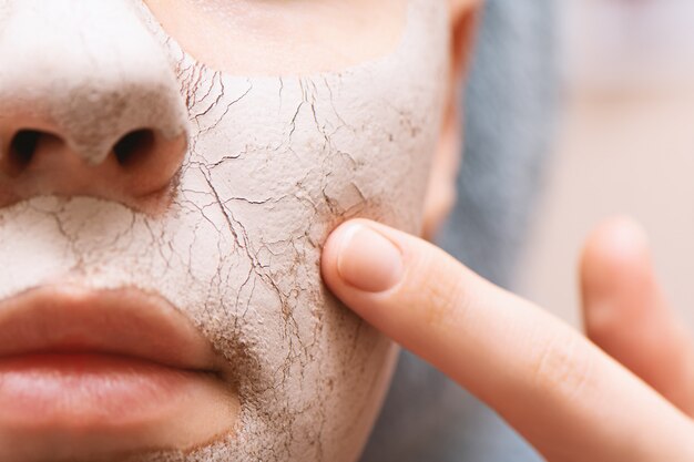 Masque facial à l'argile sur le visage féminin, gros plan.