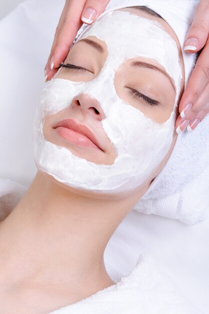 Masque facial pour jeune femme dans le salon de gros plan de beauté