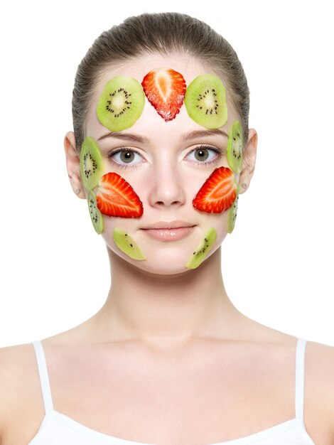 Masque de fraise aux fruits de fraise et de kiwi sur un jeune visage de belle femme isolée sur blanc