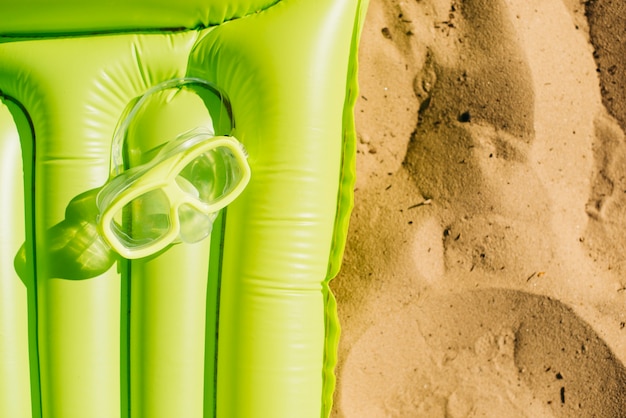 Photo gratuite masque de plongée sur un matelas sur le sable