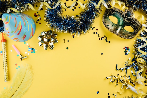 Masque de plume de carnaval mascarade avec matériel de décoration de fête et chapeau de fête sur fond jaune