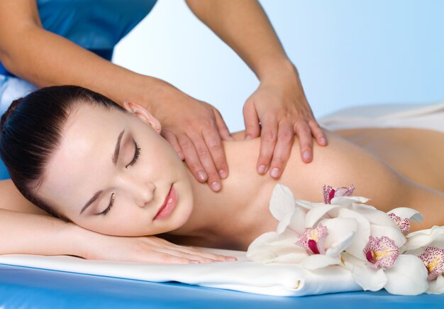 Massage de l'épaule pour la belle jeune femme dans le salon spa - horizontal