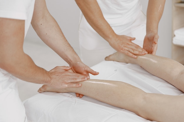Le massage à quatre mains. Concept de soins de santé et de beauté féminine. Deux masseuses font un double massage d'une fille. Femme dans un salon de spa.