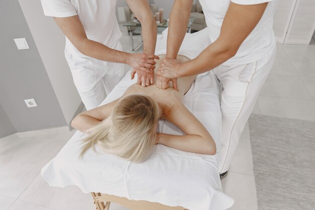 Le massage à quatre mains. Concept de soins de santé et de beauté féminine. Deux masseuses font un double massage d'une fille. Femme dans un salon de spa.