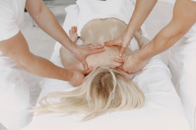 Le massage à quatre mains. Concept de soins de santé et de beauté féminine. Deux masseuses font un double massage d'une fille. Femme dans un salon de spa.