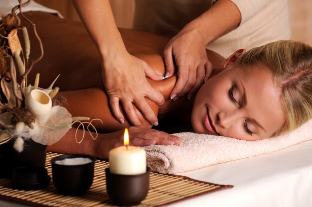 Masseur faisant un massage sur l'épaule féminine dans le salon de beauté