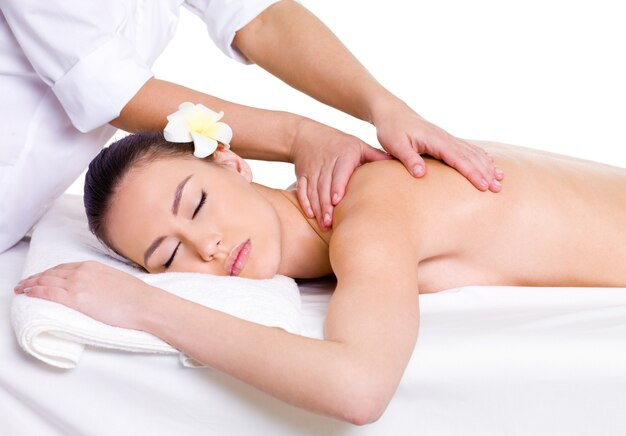 Le masseur professionnel fait un massage relaxant d'un dos à la belle jeune femme - fond blanc