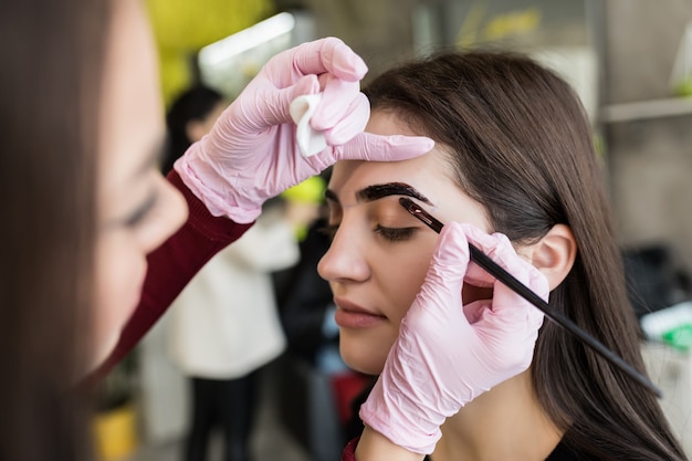 Master en gants blancs travaillent à balck sourcils dans un salon de beauté