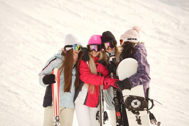 Matériel de ski entre les mains des filles. Couleurs vives sur les vêtements de ski. Les filles passent un bon moment ensemble.