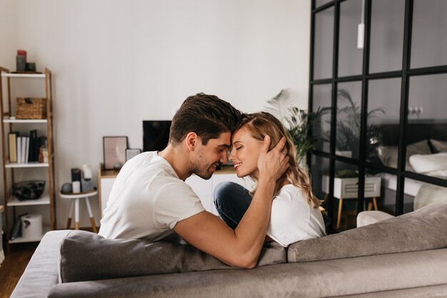 Matinée romantique à la maison avec un intérieur moderne. Deux personnes mignonnes et charmantes avec le sourire et les yeux fermés apprécient le temps ensemble.