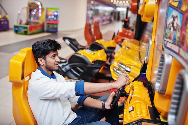 Photo gratuite un mec asiatique concourt sur une machine de simulateur de course de jeu d'arcade speed rider