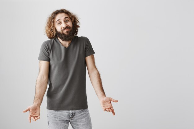 Mec barbu non dérangé du Moyen-Orient haussant les épaules et souriant insouciant