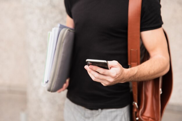 Mec en chemise noire regardant son téléphone