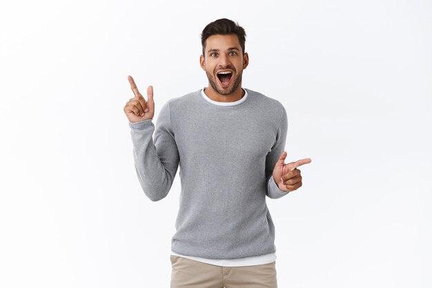 Un mec joyeux et excité repère une promo intéressante et partage avec nous Bel homme souriant pointant sur le côté comme faisant du shopping en magasin avec des choix variés bouche ouverte regard fasciné amusé et heureux