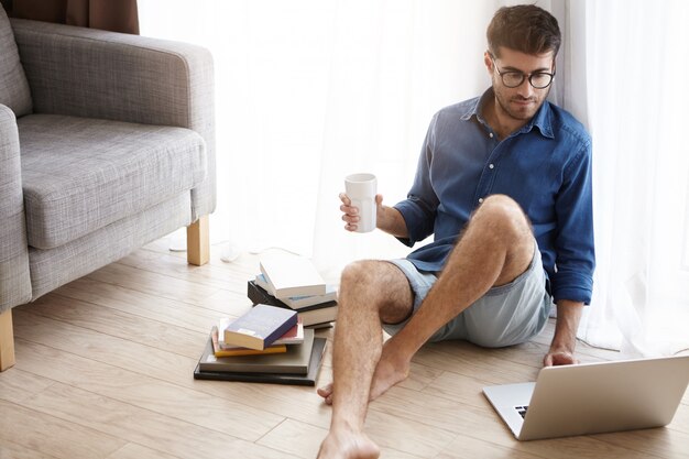 Un mec à la mode attrayant aime passer du temps à la maison, aime l'atmosphère domestique