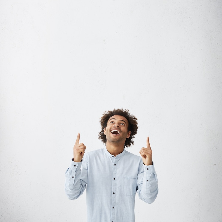 Photo gratuit mec portant une chemise élégante blanche pointant et regardant avec sourire vers le haut
