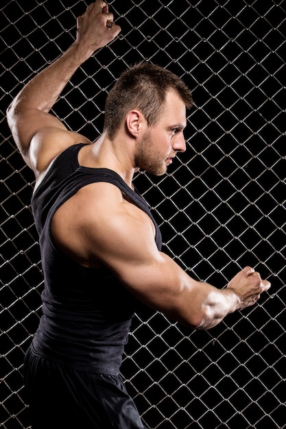 Mec puissant montrant ses muscles sur la clôture