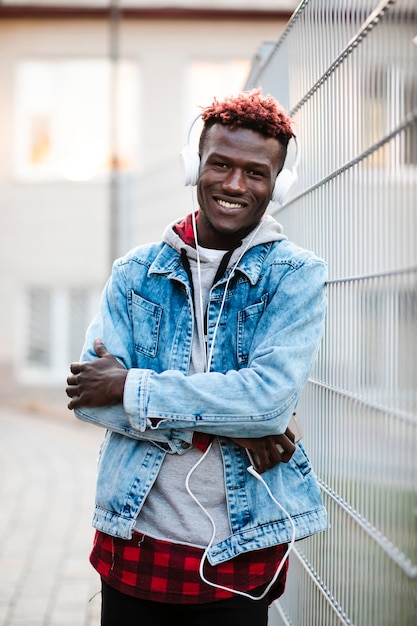 Photo gratuite mec souriant avec des écouteurs et des bras croisés