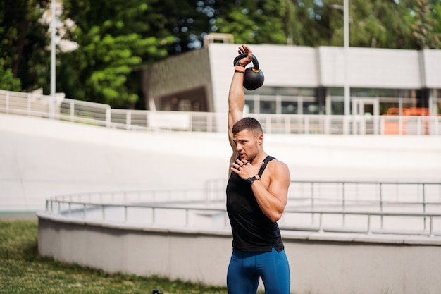 Mec sportif s'entraînant avec kettlebell. Photo d'un bel homme avec un bon physique. Force et motivation.