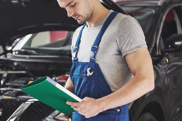 mécanicien automobile ou forgeron avec presse-papiers à l'atelier.
