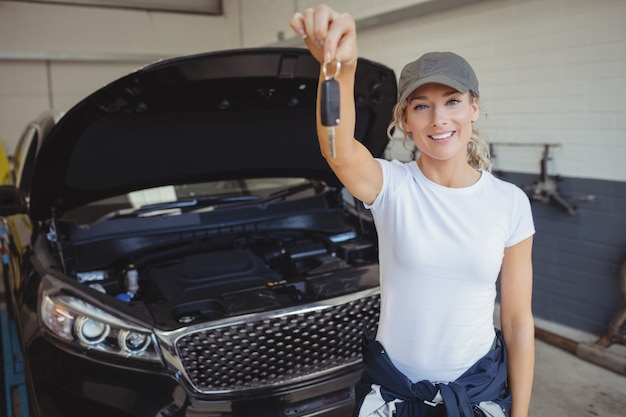 Photo gratuite mécanicien féminin dans le garage tenant la clé de voiture