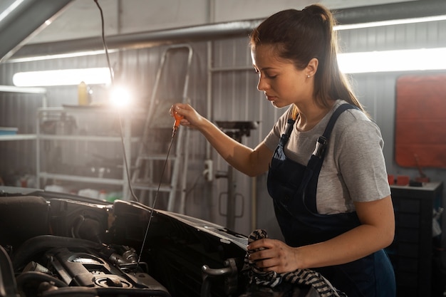 Mécanicien féminin travaillant dans le magasin sur une voiture