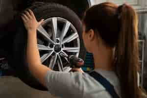 Photo gratuite mécanicien féminin travaillant dans le magasin sur une voiture