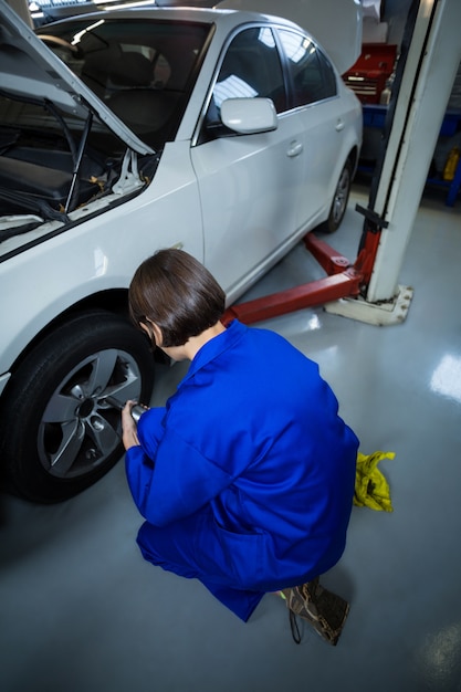 Photo gratuite mécanicien femme fixant une roue de voiture avec une clé pneumatique