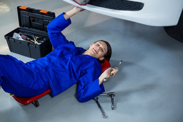 mécanicien Femme souriante lors de la réparation d&#39;une voiture