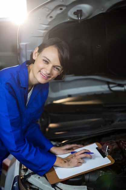 mécanicien Femme souriante tout en préparant une liste de contrôle