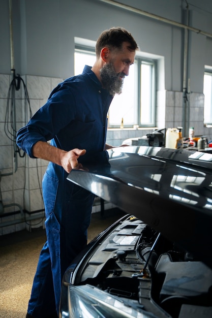 Mécanicien masculin travaillant dans un atelier de réparation automobile sur une voiture